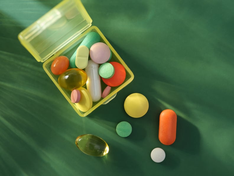 Clear box of colorful pills on a green backdrop.